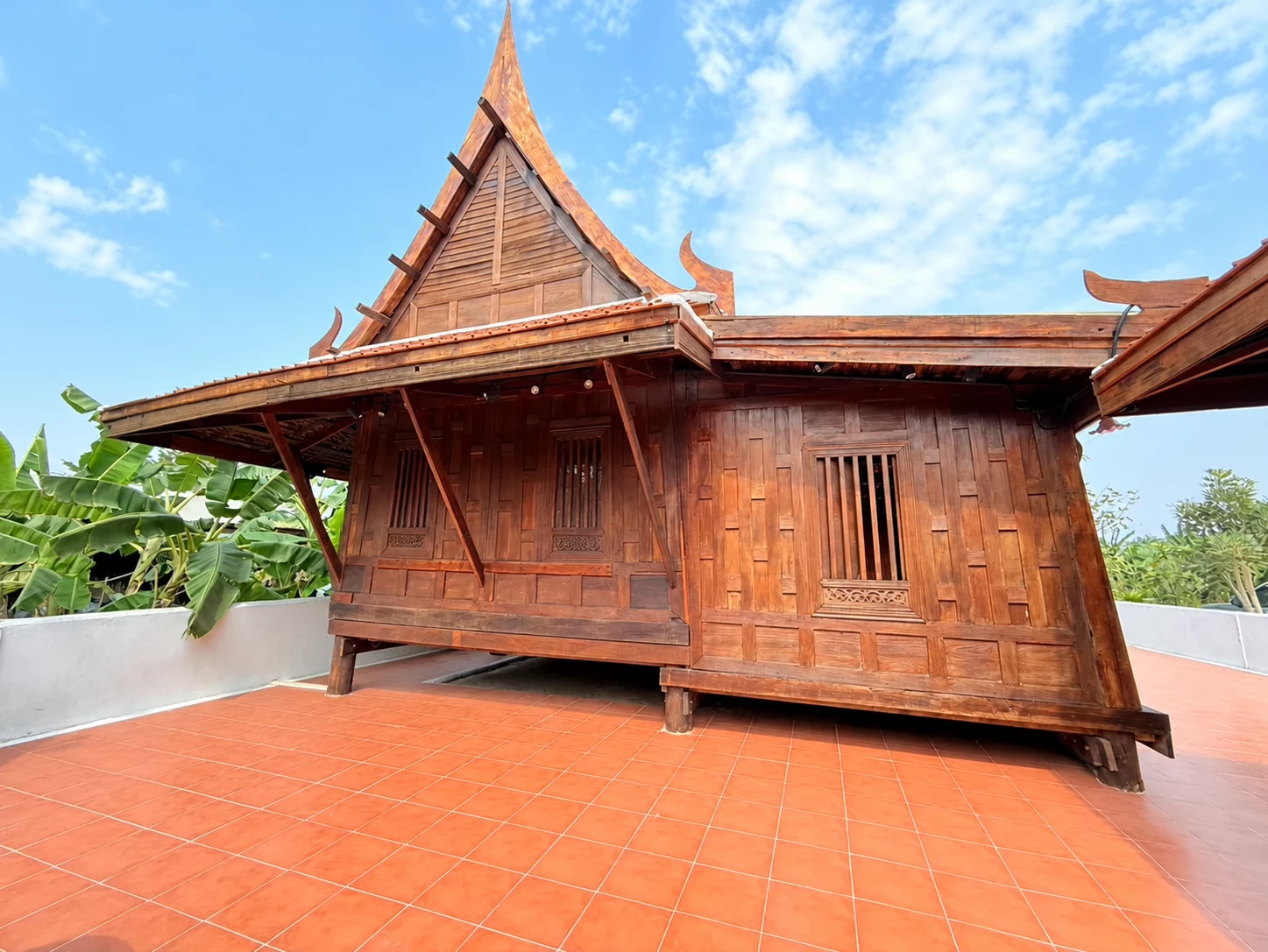 หน้าจั่วเรือนไม้กับหน้าต่างและค้ำยันเหนือพื้นกระเบื้องสีส้ม
