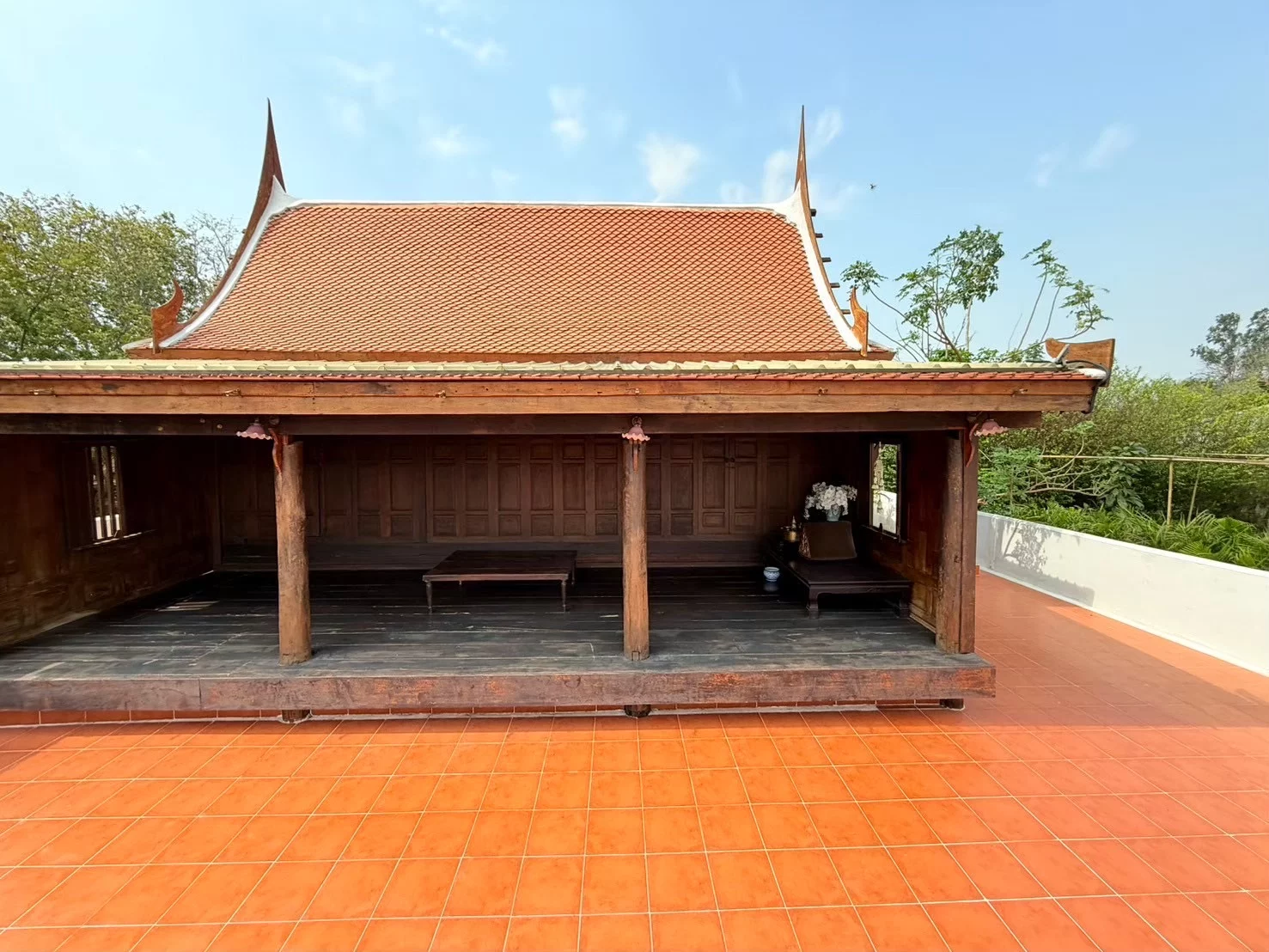 เรือนไม้ด้านหน้า หลังคากระเบื้องสีดินเผา และลานกระเบื้องสี่เหลี่ยม