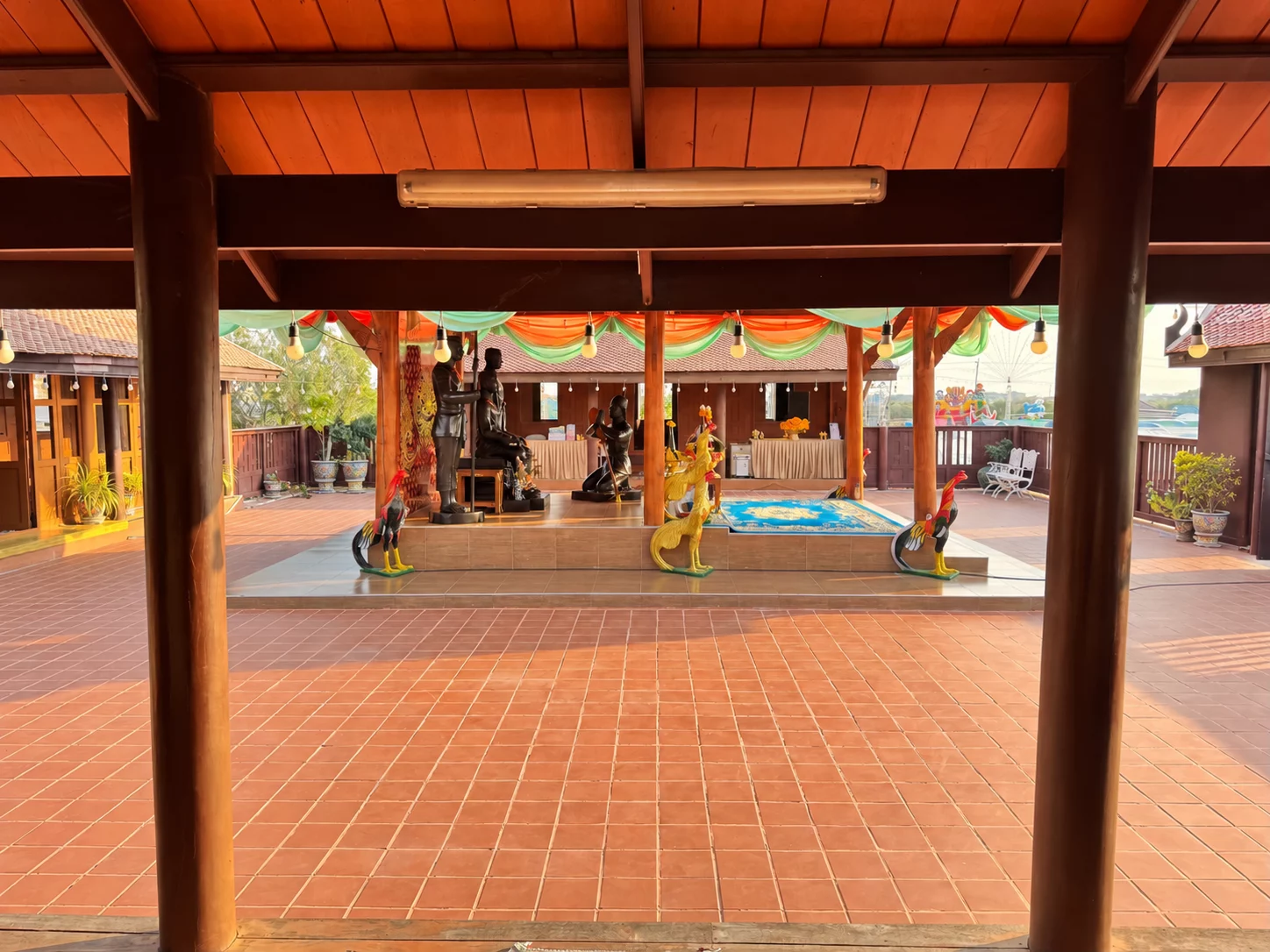 เสาไม้ด้านหน้าเป็นกรอบมองไปยังพื้นลานและจุดสักการะ