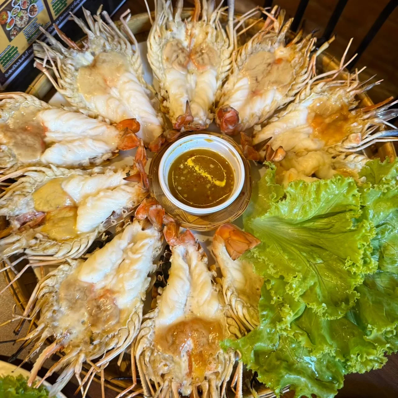กุ้งเผาผ่าซีกจัดเรียงบนจานรองสานรอบถ้วยน้ำจิ้ม